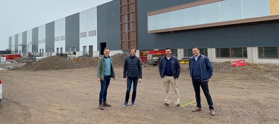From left to right: Oscar von Konow (COO NA-KD), Fred Skantze (Head of Fulfillment NA-KD), Nicklas Raask (Project Manager Empir Industry), Mikael Hedlund (Business Area Manager Infrastructure Empir Industry) in front of NA-KD's ongoing construction of the new Nordic automated robot warehouse in Landskrona, Sweden.